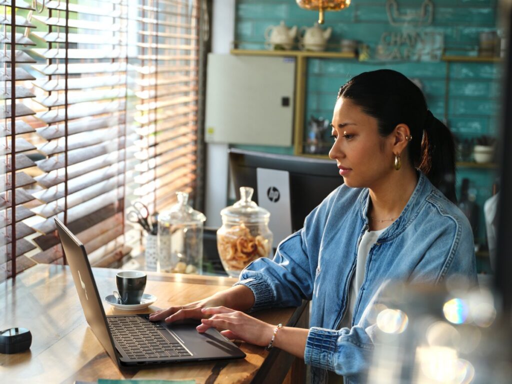 Woman typing on a laptop, sat at a table
